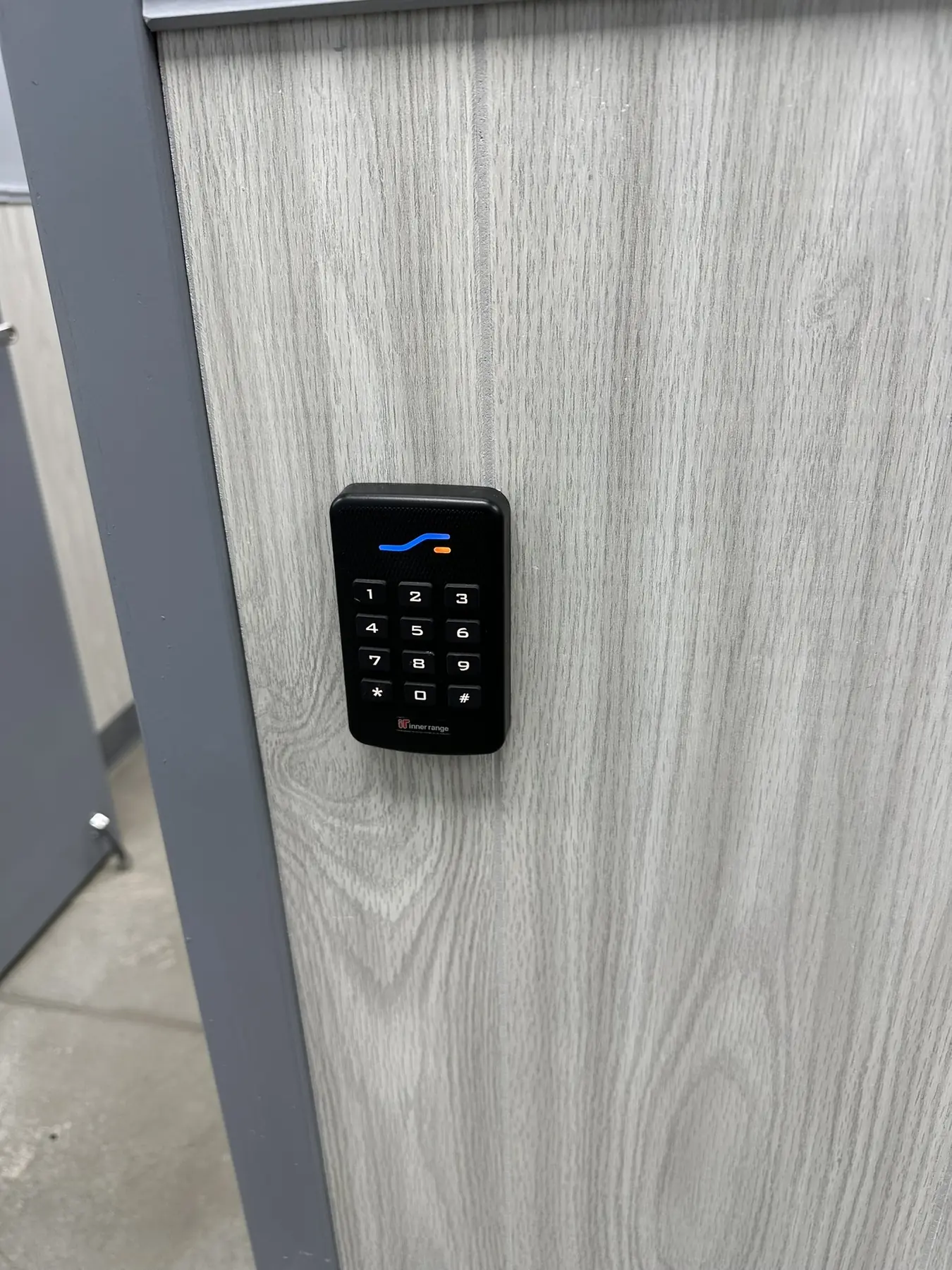 Black access control keypad and credential reader mounted beside a door